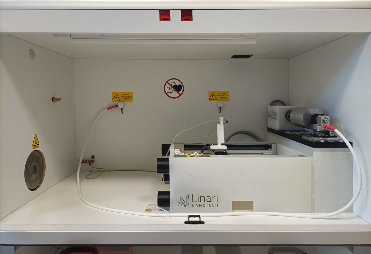 Chamber view of All-in-One electrospinning machine by Linari Nanotech. rotary collector and gantry with high voltage generator, drum collector on the right and needle are shown.