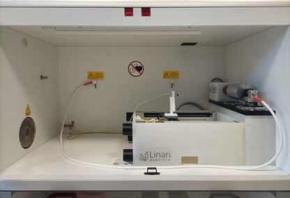 Chamber view of All-in-One electrospinning machine by Linari Nanotech. rotary collector and gantry with high voltage generator, drum collector on the right and needle are shown.
