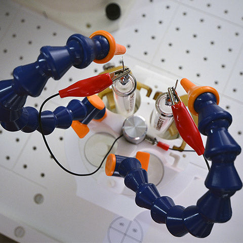 A close-up of RtAdvanced needle assembly by Linari Nanotech. Blue flexible cleaning gas pipe with orange nozzles are used to send compressed gas to clean electrospinning needles to prevent clogging. Glass syringes 50 ml with luer lock. Red alligator clips to provide high voltage.